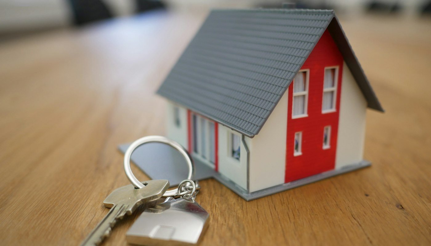A small model house and a set of keys on a table