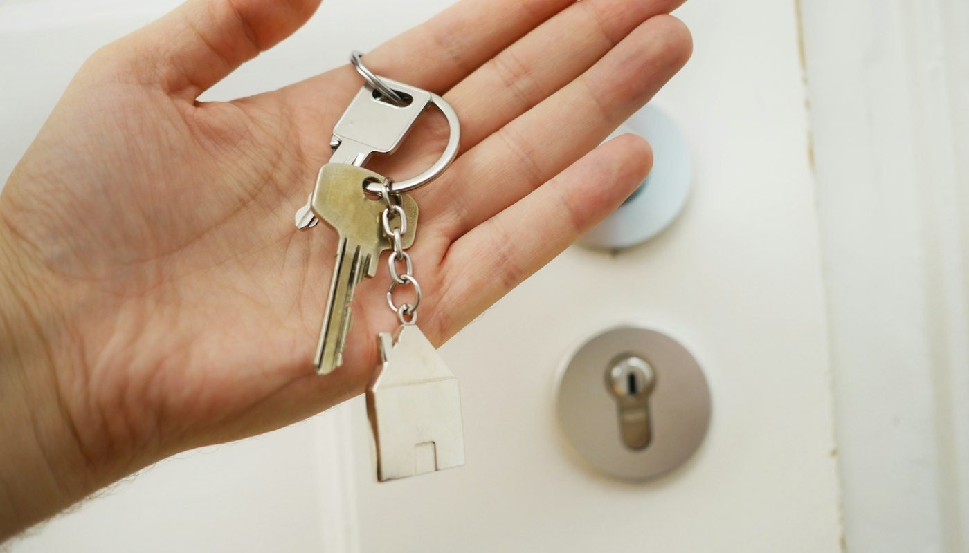 A hand holding a set of house keys at a front door